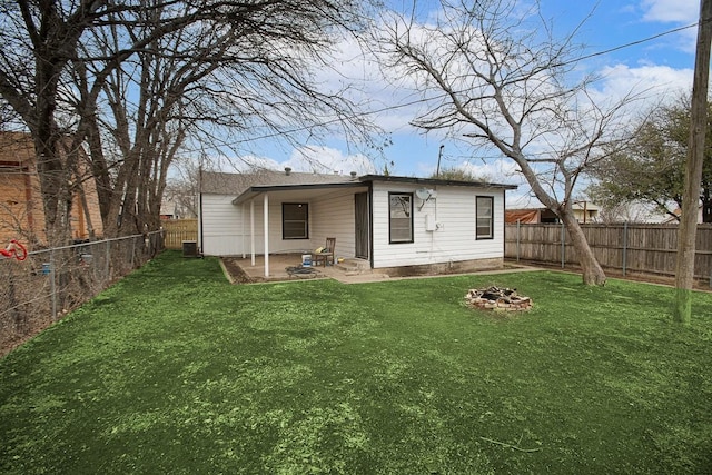 rear view of house featuring central air condition unit, a yard, a fire pit, and a fenced backyard