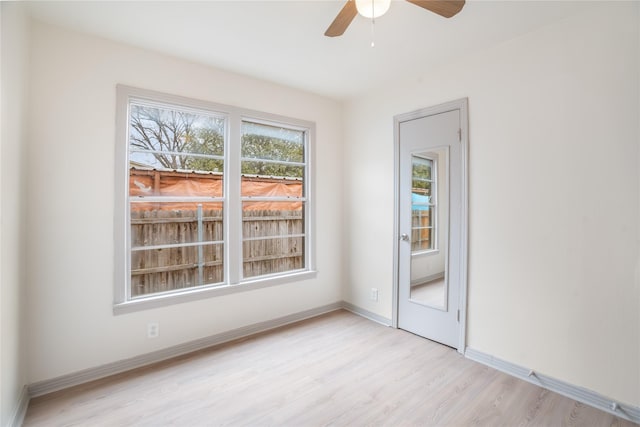 spare room featuring a ceiling fan, light wood-style floors, and baseboards