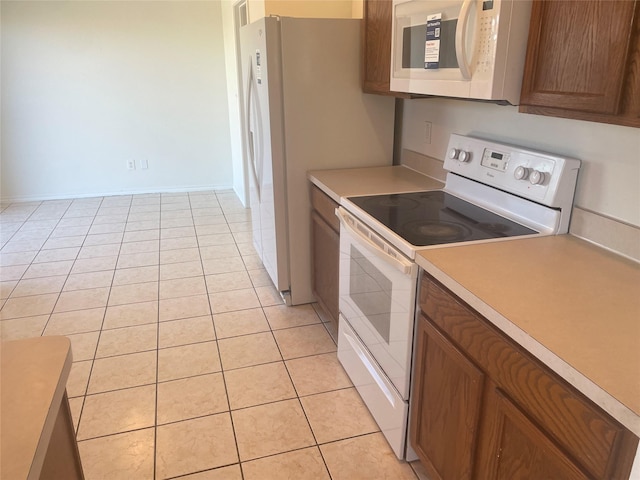 kitchen featuring light tile patterned floors, white appliances, brown cabinetry, and light countertops