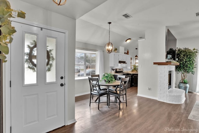 dining area featuring visible vents, lofted ceiling, a fireplace, dark wood-style flooring, and a notable chandelier