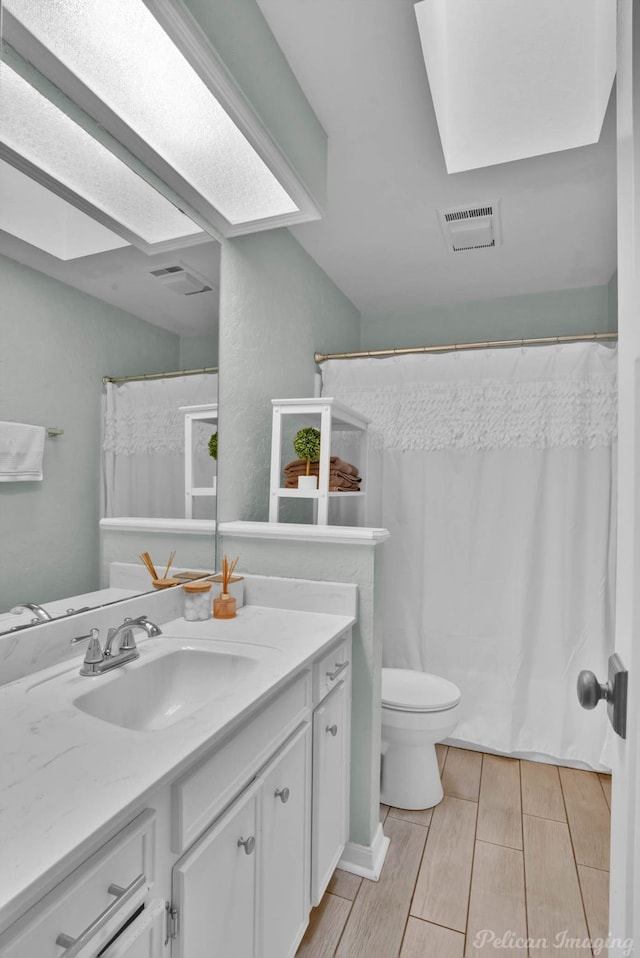 full bath featuring visible vents, toilet, vanity, and wood finish floors