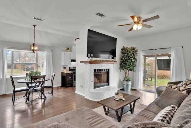 living room featuring visible vents, a brick fireplace, and wood finished floors