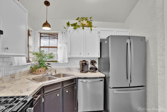 kitchen with a sink, hanging light fixtures, appliances with stainless steel finishes, white cabinetry, and backsplash