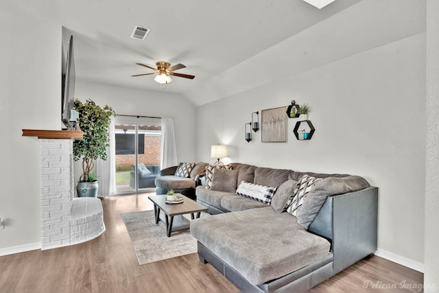 living area with baseboards, wood finished floors, visible vents, and ceiling fan