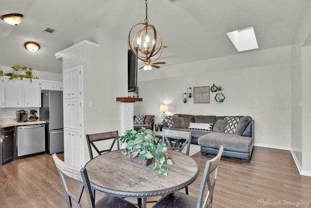 dining space with light wood-type flooring, baseboards, visible vents, and a ceiling fan