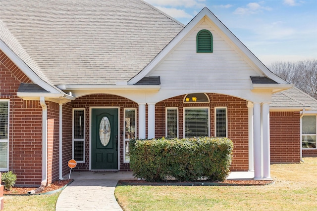 property entrance featuring brick siding and roof with shingles