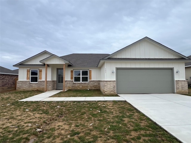 view of front of house featuring brick siding, an attached garage, driveway, and a front yard