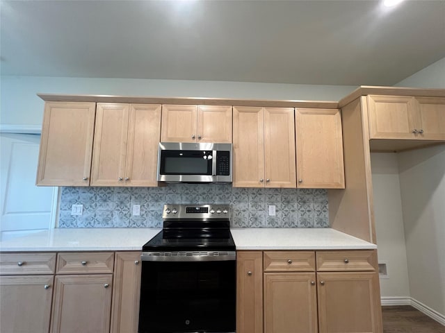 kitchen with stainless steel microwave, black range with electric cooktop, light brown cabinets, and backsplash