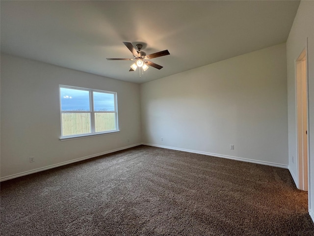 spare room featuring baseboards, dark colored carpet, and ceiling fan