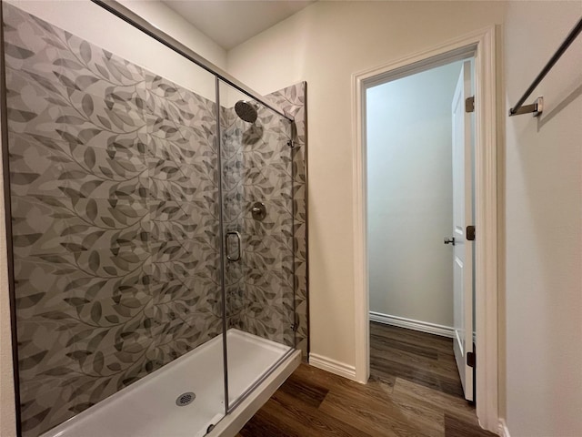 full bathroom featuring a stall shower, baseboards, and wood finished floors