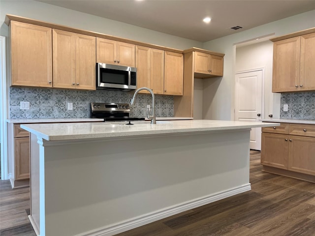 kitchen with visible vents, an island with sink, dark wood-style flooring, stainless steel appliances, and decorative backsplash