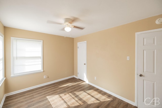 empty room featuring ceiling fan, baseboards, and wood finished floors