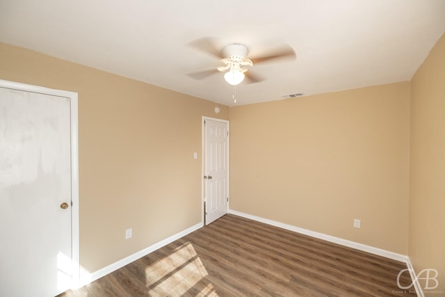 empty room featuring ceiling fan, visible vents, baseboards, and wood finished floors