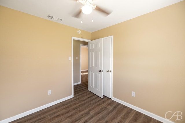 empty room with ceiling fan, visible vents, baseboards, and dark wood finished floors