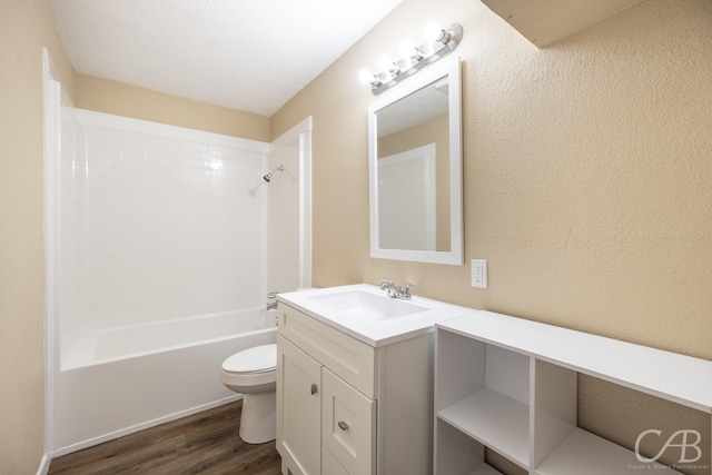 full bathroom with vanity, wood finished floors, tub / shower combination, toilet, and a textured wall