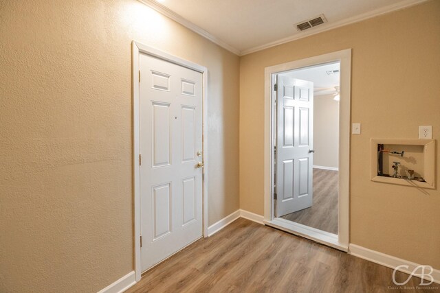 interior space featuring visible vents, baseboards, wood finished floors, and crown molding