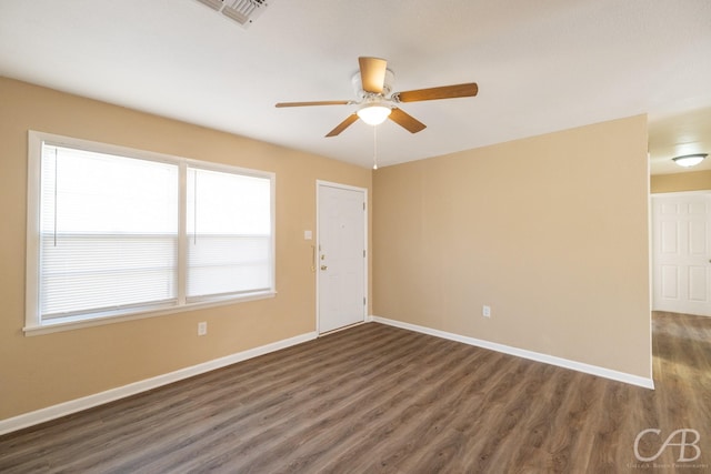 empty room with ceiling fan, visible vents, baseboards, and dark wood finished floors