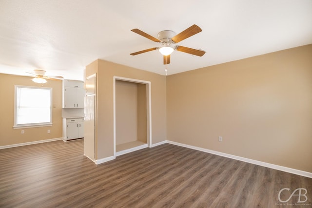 interior space with baseboards, a ceiling fan, and dark wood-style flooring