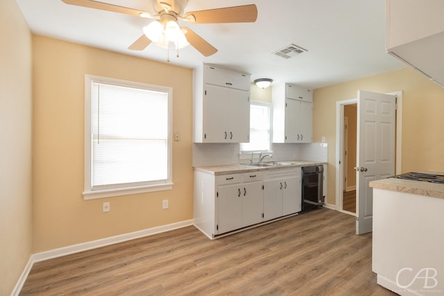 kitchen featuring visible vents, light wood-style flooring, a sink, white cabinets, and light countertops