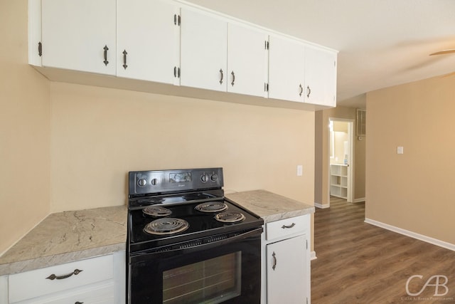 kitchen with wood finished floors, baseboards, light countertops, white cabinets, and black range with electric cooktop