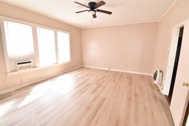 empty room featuring heating unit, cooling unit, baseboards, light wood finished floors, and crown molding