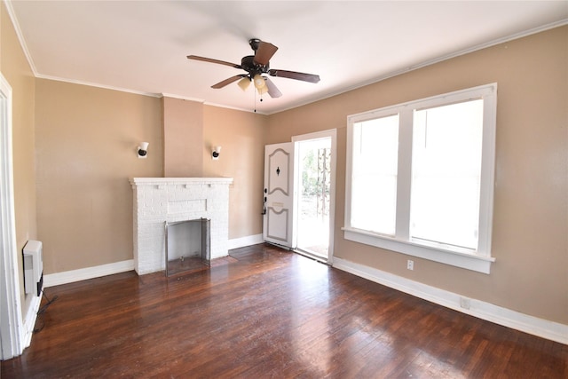 unfurnished living room with baseboards, a brick fireplace, dark wood finished floors, and crown molding