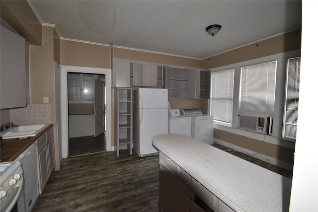 kitchen with white appliances, dark wood-style flooring, ornamental molding, a sink, and washer and clothes dryer