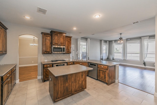 kitchen with visible vents, backsplash, appliances with stainless steel finishes, a peninsula, and arched walkways