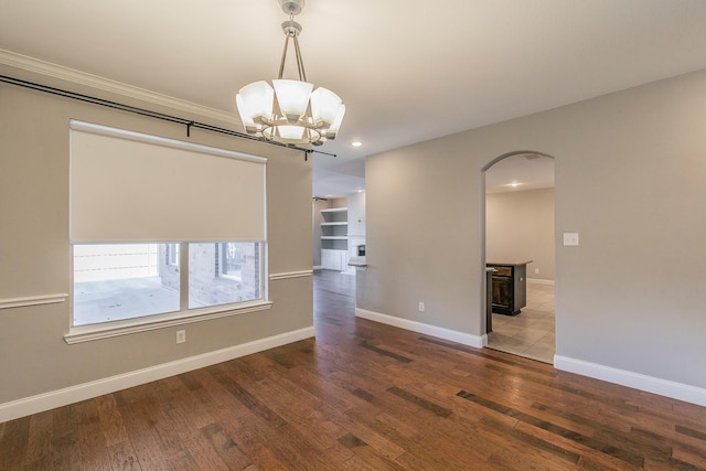 spare room with arched walkways, a chandelier, wood finished floors, recessed lighting, and baseboards