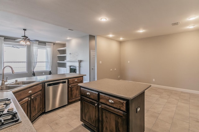 kitchen featuring stainless steel appliances, a sink, a ceiling fan, light tile patterned floors, and a fireplace