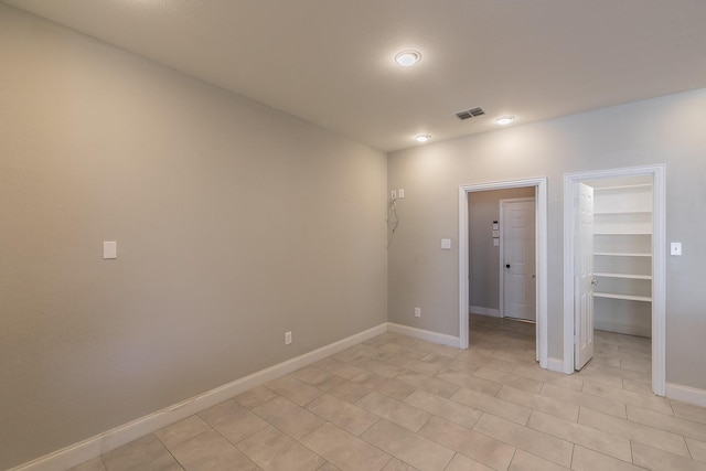 spare room featuring light tile patterned floors, visible vents, and baseboards