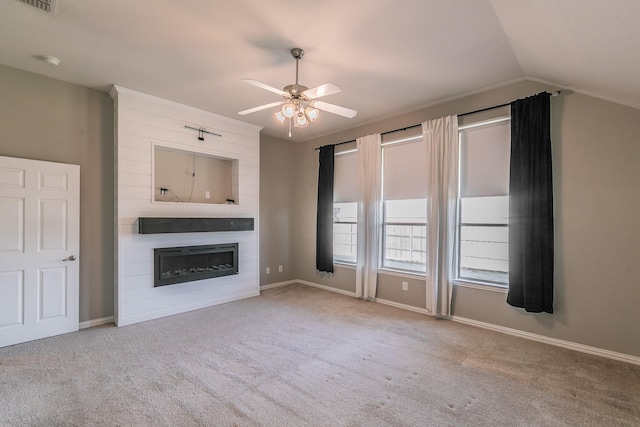 unfurnished living room featuring baseboards, ceiling fan, vaulted ceiling, carpet flooring, and a glass covered fireplace