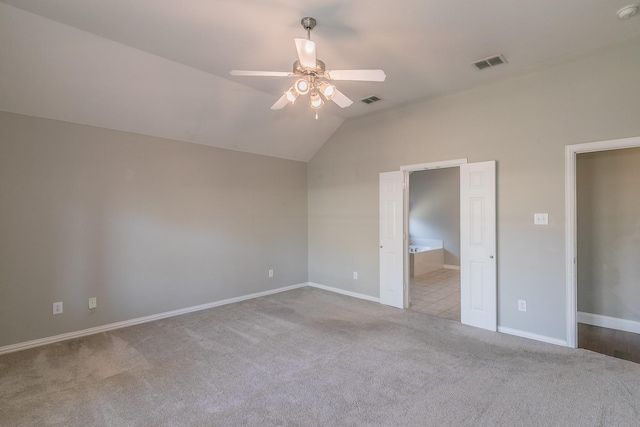 unfurnished bedroom with carpet, vaulted ceiling, baseboards, ensuite bath, and a ceiling fan