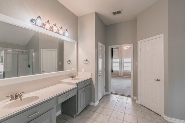 full bathroom featuring a stall shower, double vanity, tile patterned floors, baseboards, and vaulted ceiling
