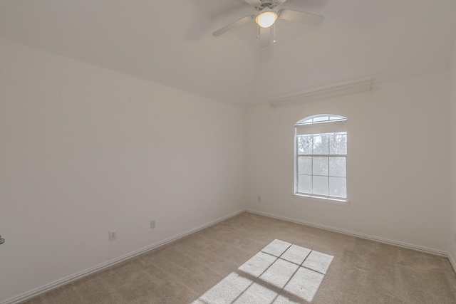 carpeted empty room featuring baseboards, ceiling fan, and vaulted ceiling