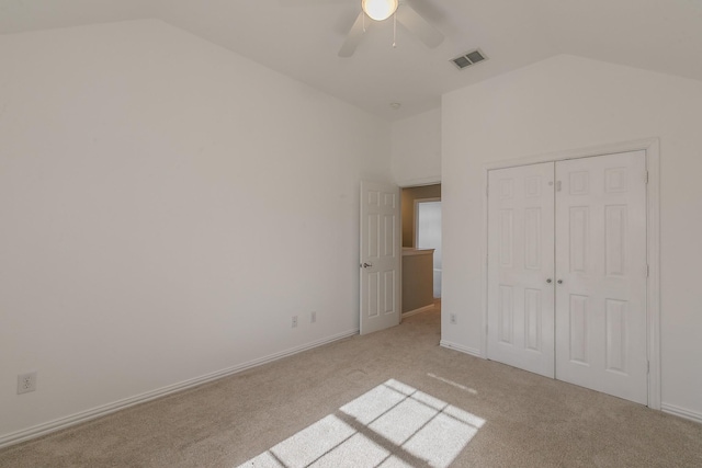 unfurnished bedroom with vaulted ceiling, light colored carpet, a closet, ceiling fan, and baseboards
