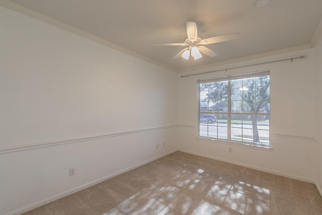 carpeted spare room with ceiling fan, baseboards, and ornamental molding