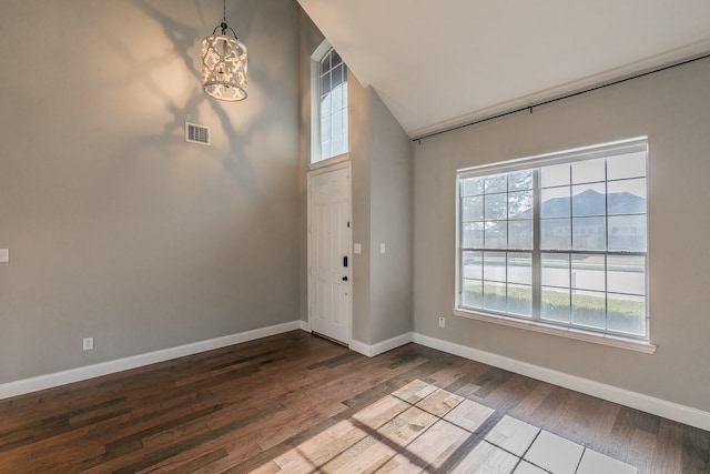entrance foyer with wood finished floors, baseboards, high vaulted ceiling, and a chandelier