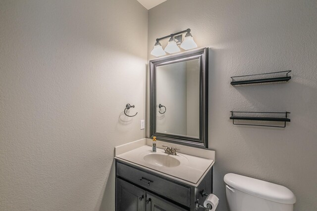 bathroom featuring vanity, toilet, and a textured wall