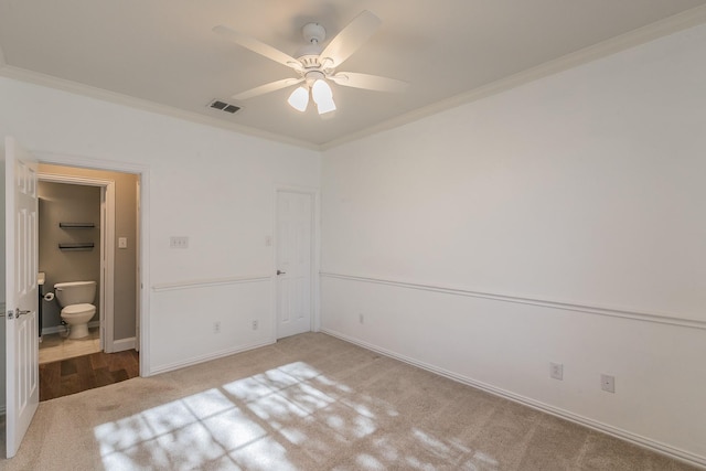unfurnished bedroom with ornamental molding, carpet flooring, baseboards, a ceiling fan, and ensuite bathroom