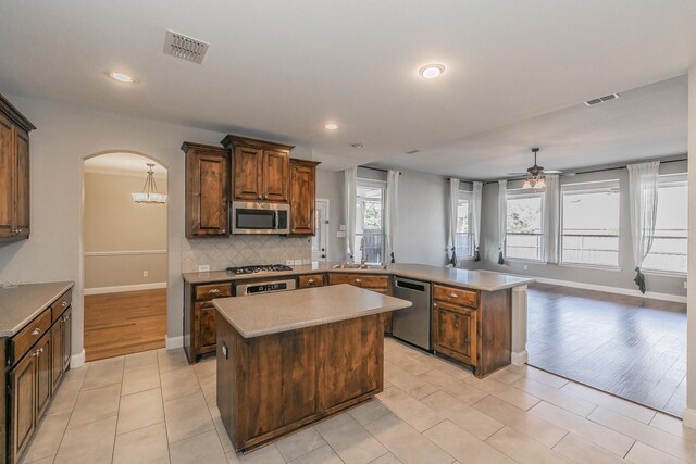 713 Cross Meadow Blvd, Mansfield, TX 76063 - kitchen featuring stainless steel appliances, a peninsula, arched walkways, a ceiling fan, and backsplash