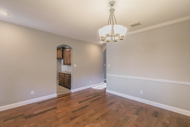 empty room with arched walkways, baseboards, a chandelier, wood finished floors, and crown molding