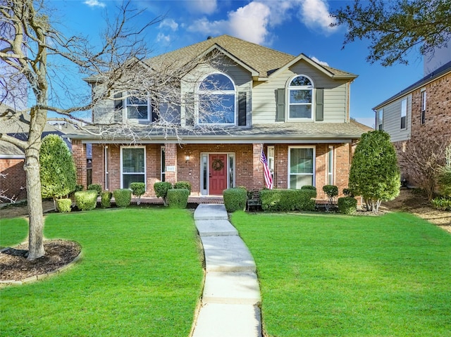 traditional home with brick siding, a shingled roof, and a front lawn