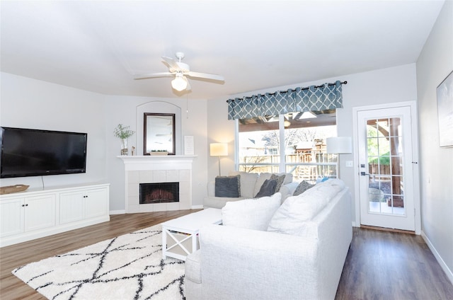 living room with ceiling fan, baseboards, wood finished floors, and a fireplace