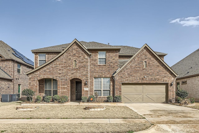 traditional-style home with a garage, brick siding, driveway, and a shingled roof