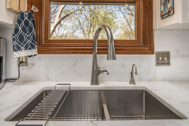 room details featuring light stone countertops, tasteful backsplash, and a sink