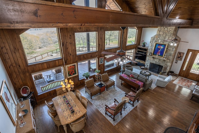 living room featuring a ceiling fan, high vaulted ceiling, beam ceiling, a fireplace, and hardwood / wood-style flooring