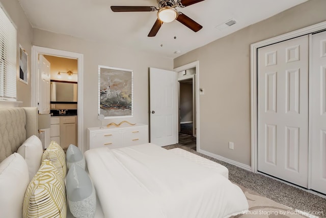 carpeted bedroom featuring baseboards, visible vents, ensuite bath, a sink, and ceiling fan