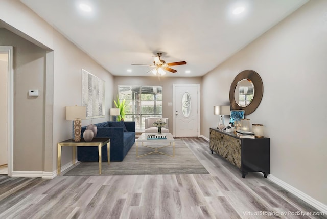 living area featuring ceiling fan, baseboards, and wood finished floors