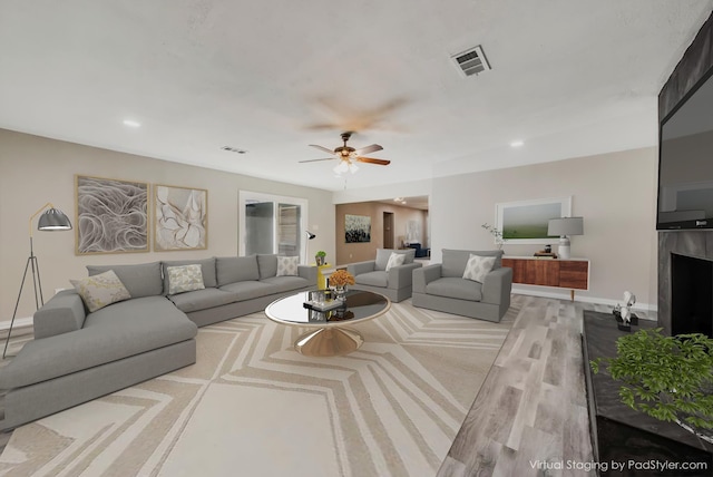 living room with visible vents, a ceiling fan, wood finished floors, a fireplace, and baseboards